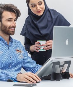 دو همکار یک خانم و یک آقا در حال کار با لپ تاپ هستند که روی زیرلپتاپی قرار دارد.