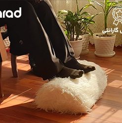زیرپایی خانگی ارگولایف جلوی مبل منزل و پاهایی روی زیرپایی قرار گرفته است