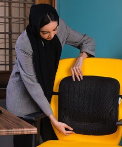 یک خانم کارمند در حال نصب پشتی طبی باراد روی صندلی اداری خود می باشد